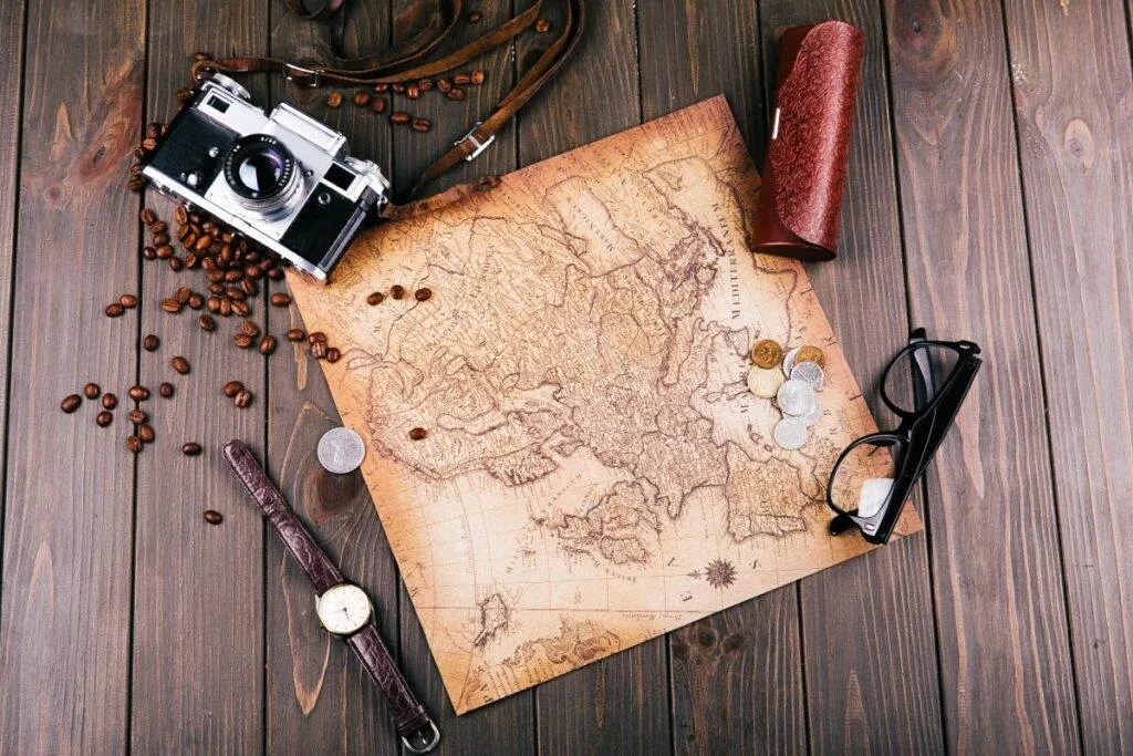 old yellow map glasses coins leather case camera watch coffee beans other spices lie wooden floor 1